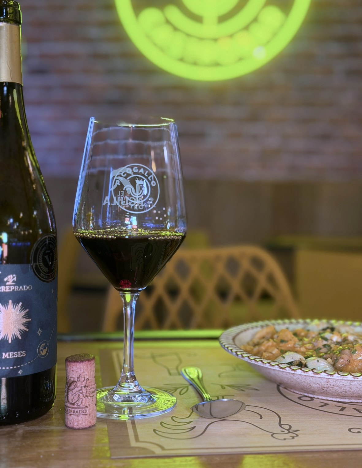 Copa de vino tinto junto a un plato de patatas a la importancia en PICOGALLO
